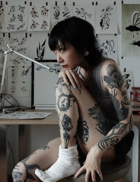 sese sitting in her Beijing studio, surrounded by tattoo sketches
